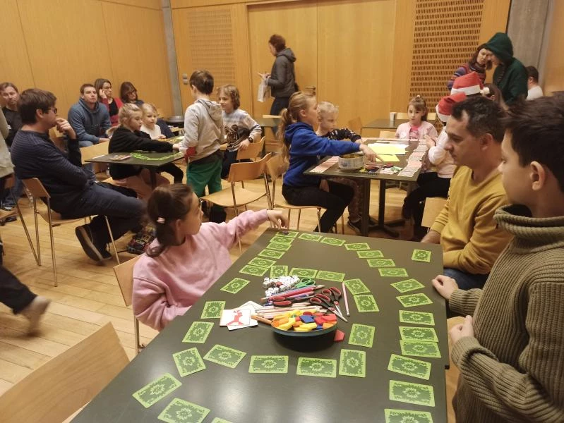 Dzieci i dorośli bawiący się przy stołach